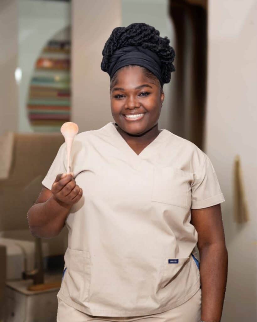 Happy spa therapist holding a massage tool at Haven Beauty House, showcasing professional skincare and wellness services in a welcoming environment.