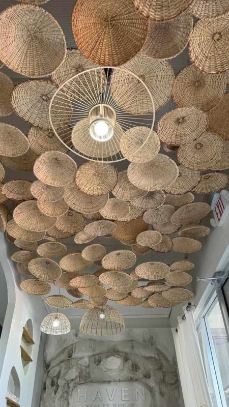 Stylish wicker ceiling light fixtures and artful woven basket decor create a cozy, natural ambiance at Haven Beauty House.