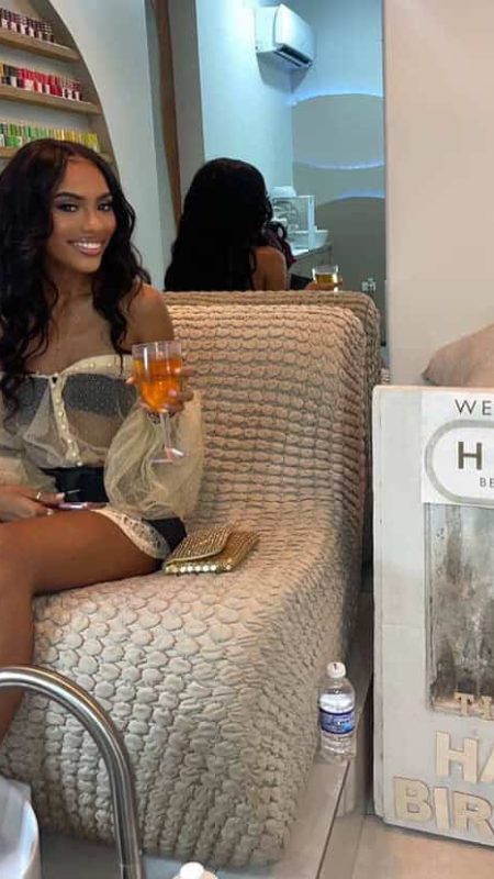 Beautiful woman enjoying a beverage at a beauty salon, with a welcoming atmosphere and cozy seating. Perfect for skincare and beauty treatments, offering a relaxing environment for clients.
